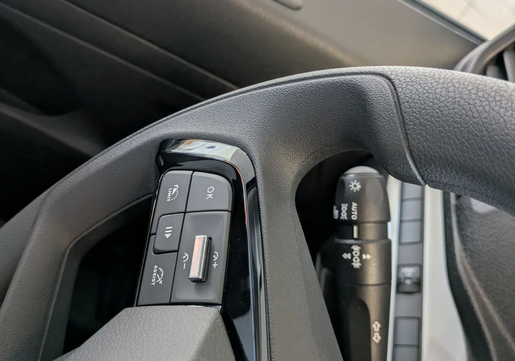 Gros plan sur les commandes au volant noir du Citroën Jumpy cabine approfondie 2025, côté gauche, avec boutons multifonctions.