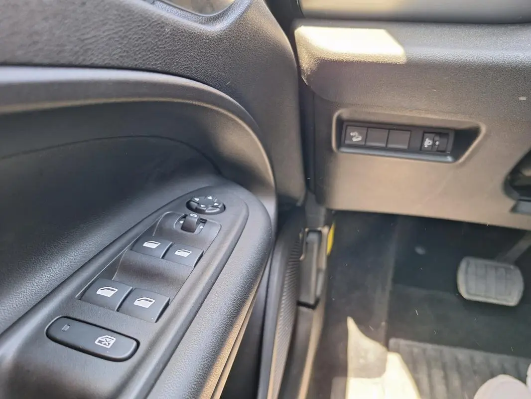 Gros plan sur les commandes des vitres électriques et rétroviseurs du côté gauche intérieur du Jeep Avenger blanc électrique 2025.