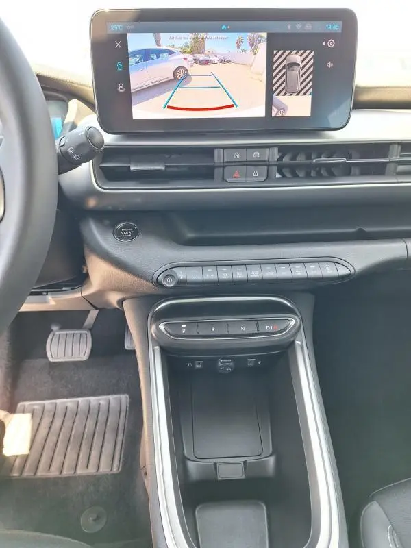 Vue intérieure du tableau de bord du Jeep Avenger électrique blanc, avec écran tactile affichant la caméra de recul et console centrale moderne.