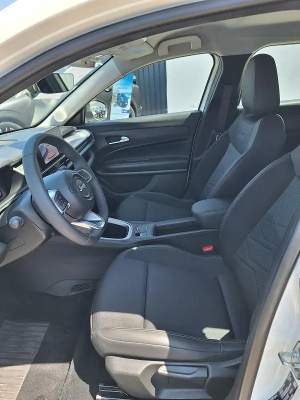 Vue intérieure côté conducteur du Jeep Avenger électrique 2025 avec sièges noirs et volant multifonction.