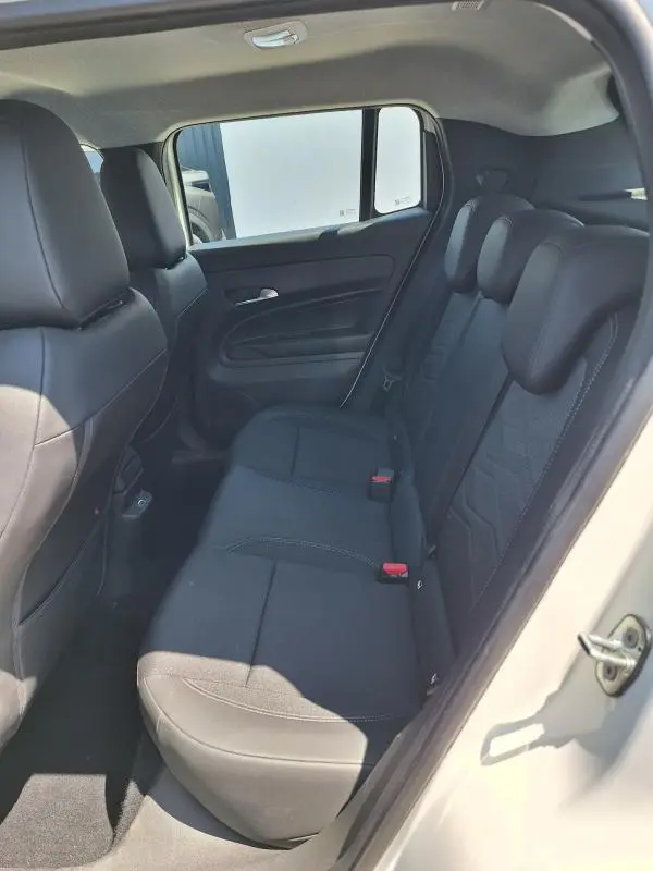 Vue intérieure côté droit des sièges arrière noirs du Jeep Avenger électrique blanc, avec appuie-têtes et ceinture de sécurité visibles.