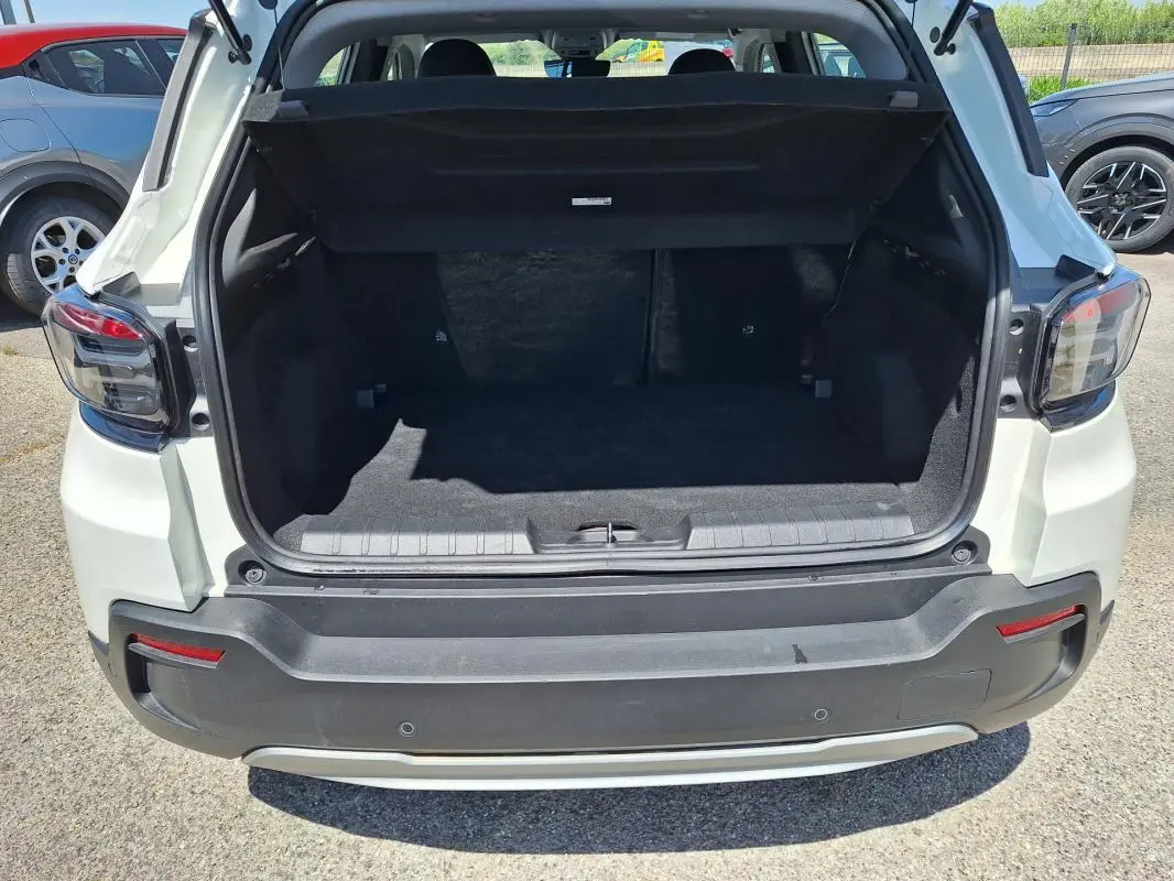 Vue arrière du coffre ouvert d'un Jeep Avenger électrique blanc, mettant en valeur l'espace de chargement.