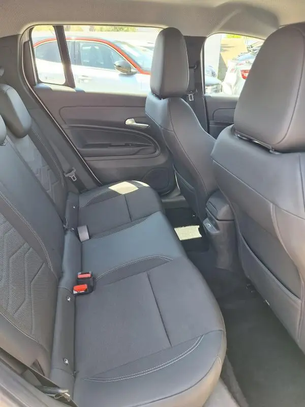 Vue intérieure des sièges arrière en tissu noir du Jeep Avenger électrique blanc, avec ceinture de sécurité et porte arrière visible.