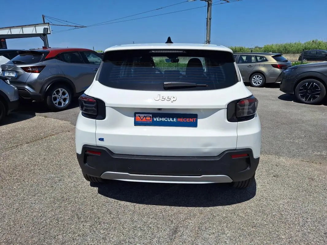 Vue arrière d'une Jeep Avenger électrique blanche 2025 avec feux arrière fumés et plaque d'immatriculation "Véhicule récent".