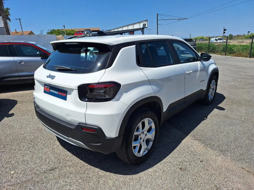Vue 3/4 arrière droite d'un Jeep Avenger électrique blanc avec jantes alliage 17 pouces et feux arrière teintés.