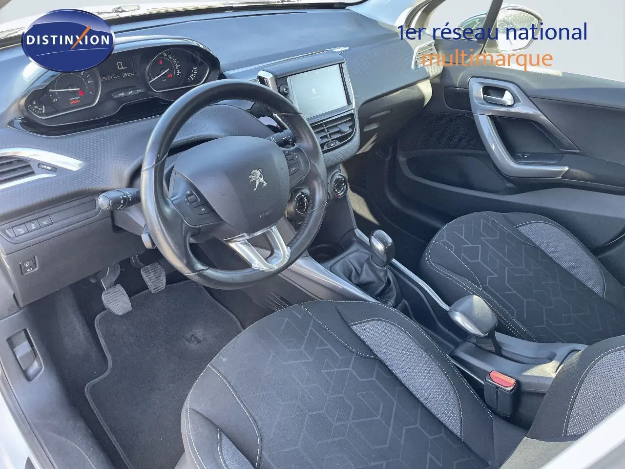 Vue intérieure côté conducteur du Peugeot 2008 blanc 2017, avec tableau de bord et sièges en tissu gris noir.