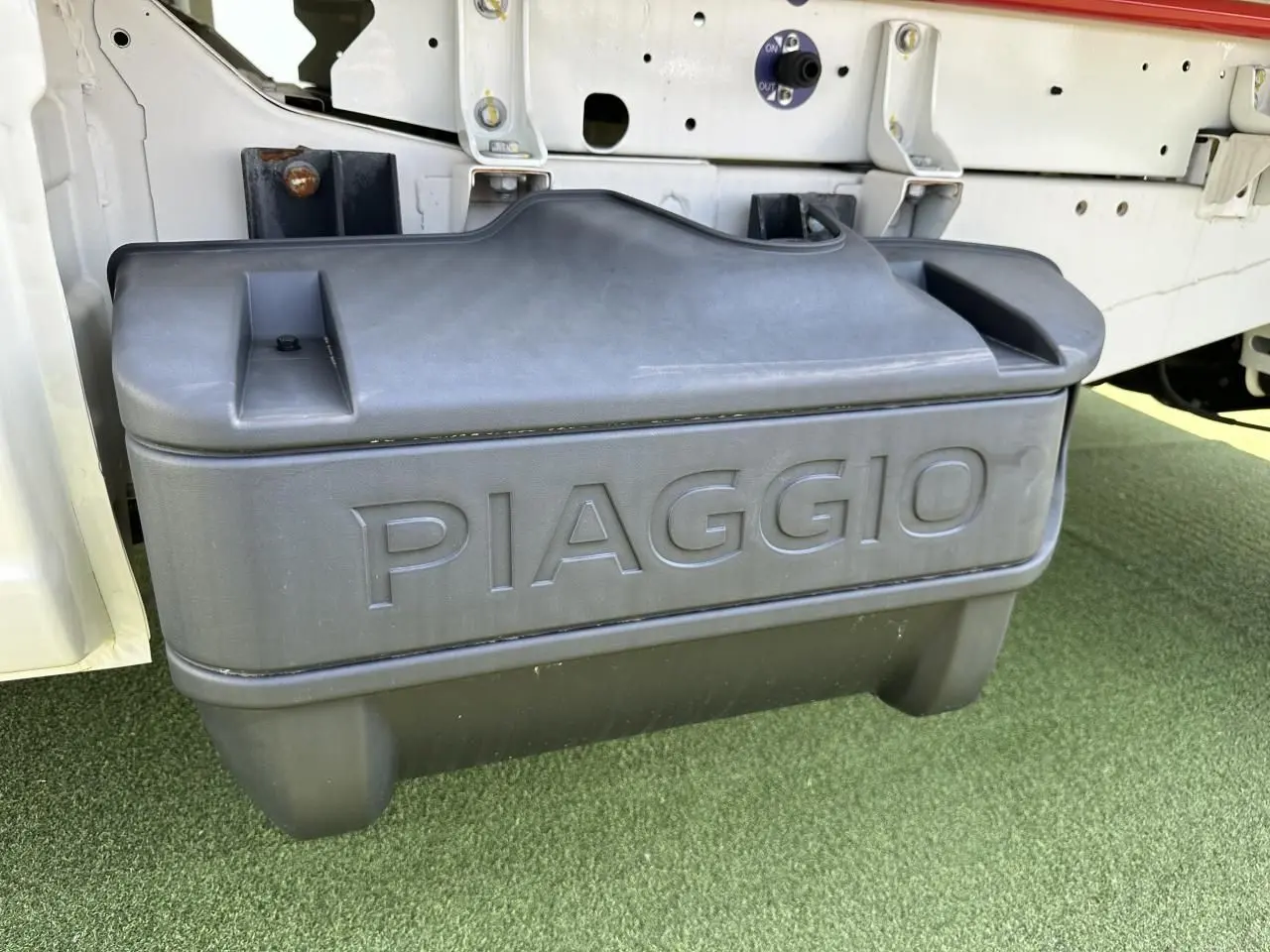 Gros plan sur le réservoir GPL noir marqué PIAGGIO sous la benne blanche du Porter NP6 côté gauche.