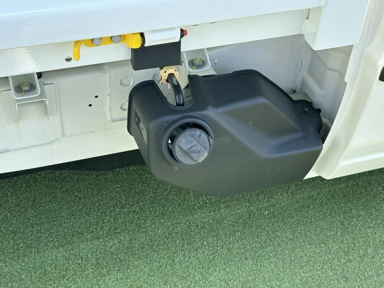 Gros plan sur le réservoir GPL noir sous la benne blanche du Piaggio Porter NP6 SWB côté gauche.