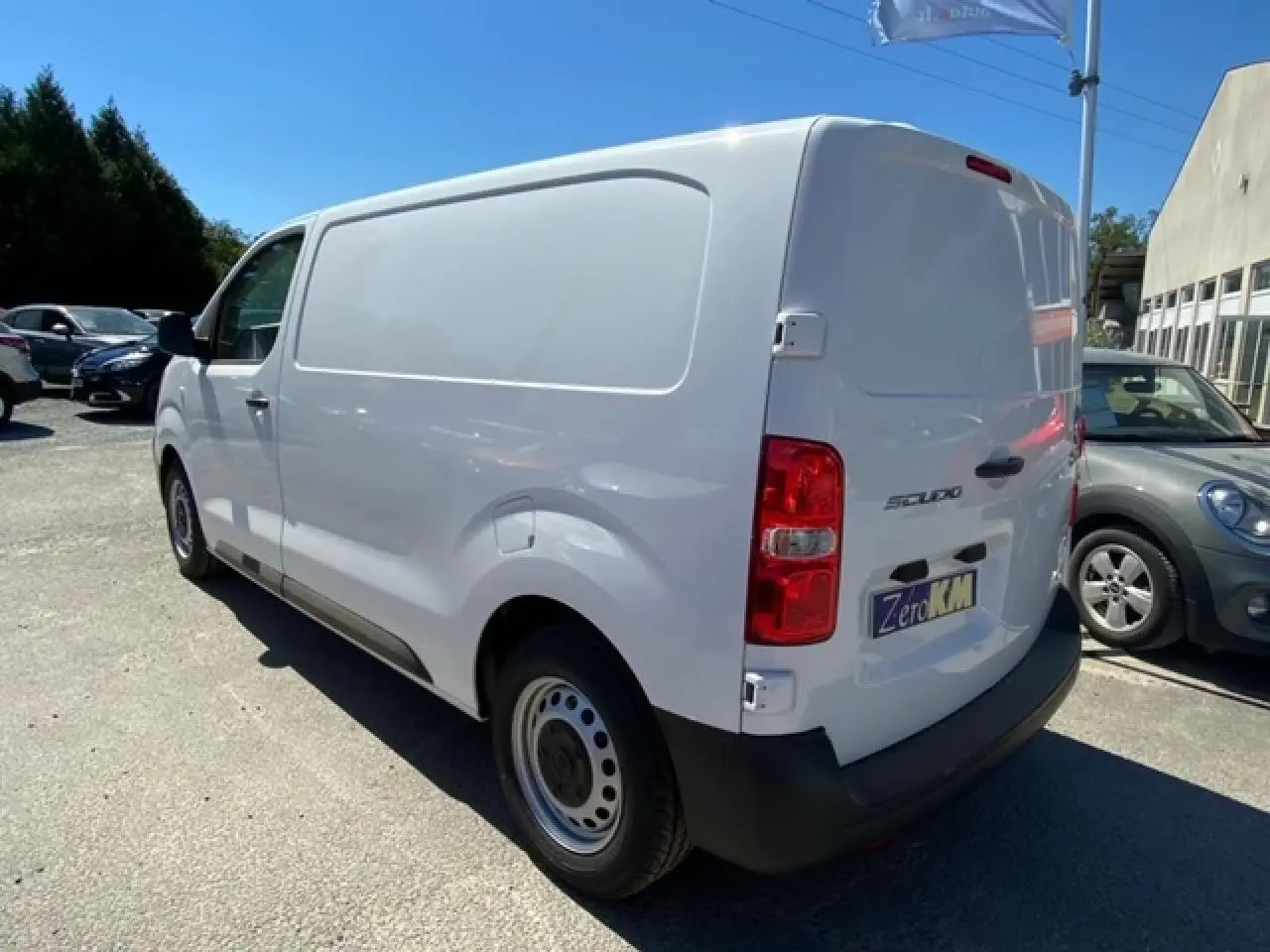 Fourgon blanc FIAT Scudo vu en 3/4 arrière droit, avec porte latérale coulissante et feux arrière rouges.
