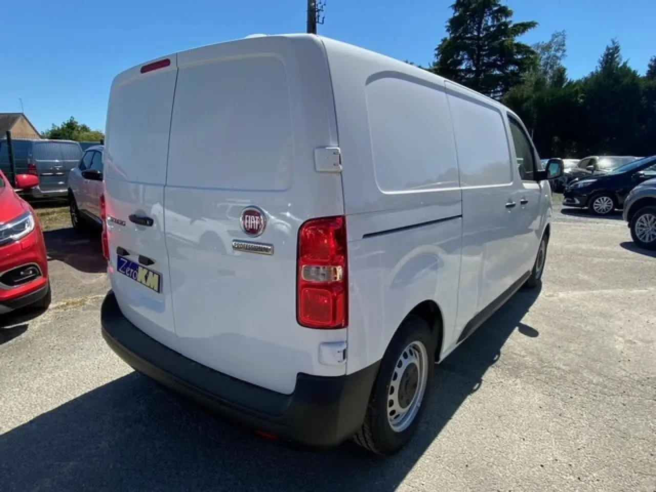 Vue 3/4 arrière droite d'un fourgon blanc FIAT Scudo 2022 avec porte latérale coulissante et feux arrière rouges.