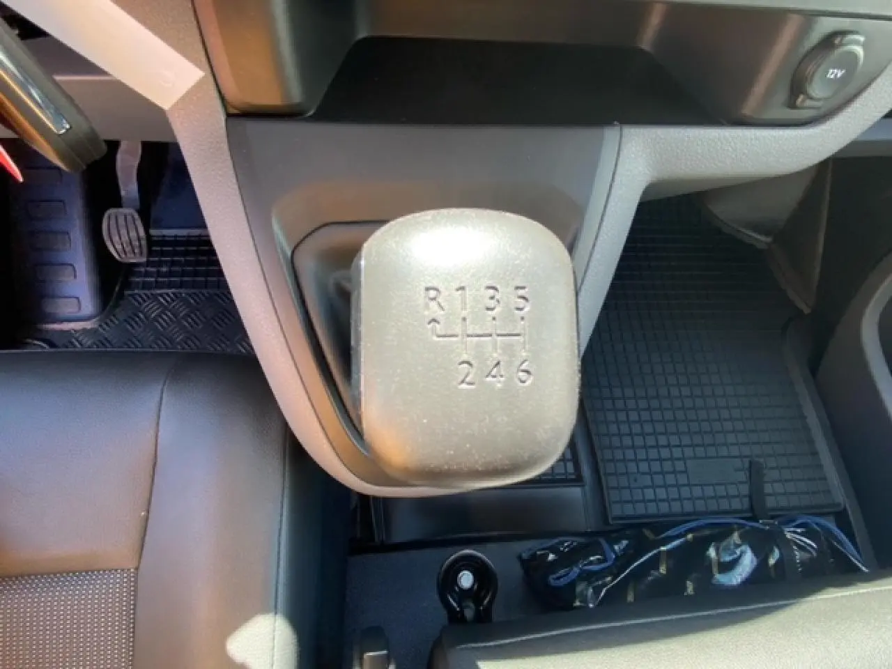 Vue intérieure rapprochée du levier de vitesses manuel du FIAT Scudo Fourgon blanc, avec sièges en cuir noir.