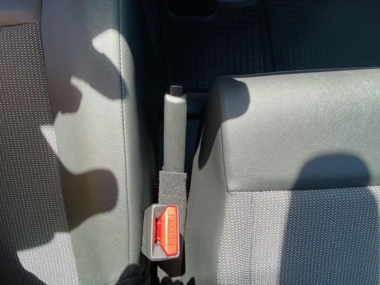 Gros plan sur la poignée de frein à main et la ceinture de sécurité entre les sièges avant gris du Fiat Scudo Fourgon blanc.