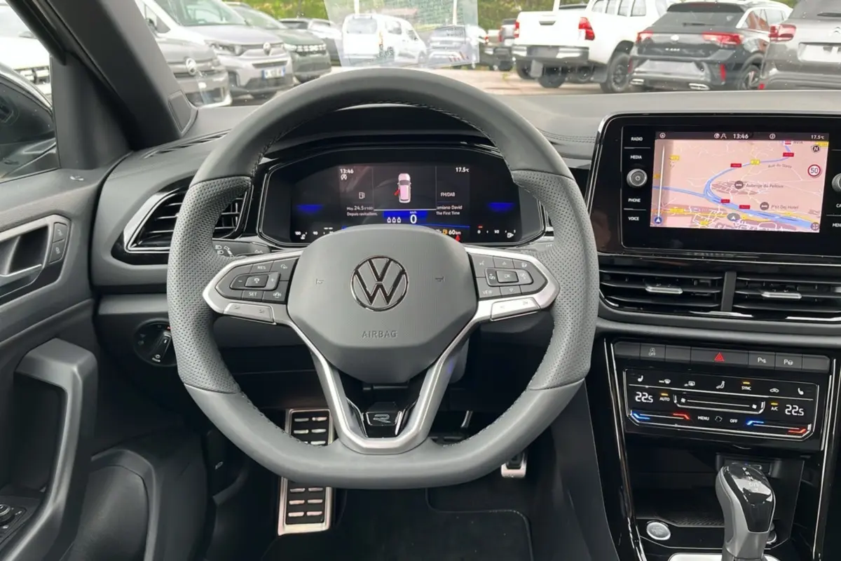Vue intérieure centrée sur le volant multifonction du Volkswagen T-Roc R-Line Black 2025 avec écran digital et navigation.