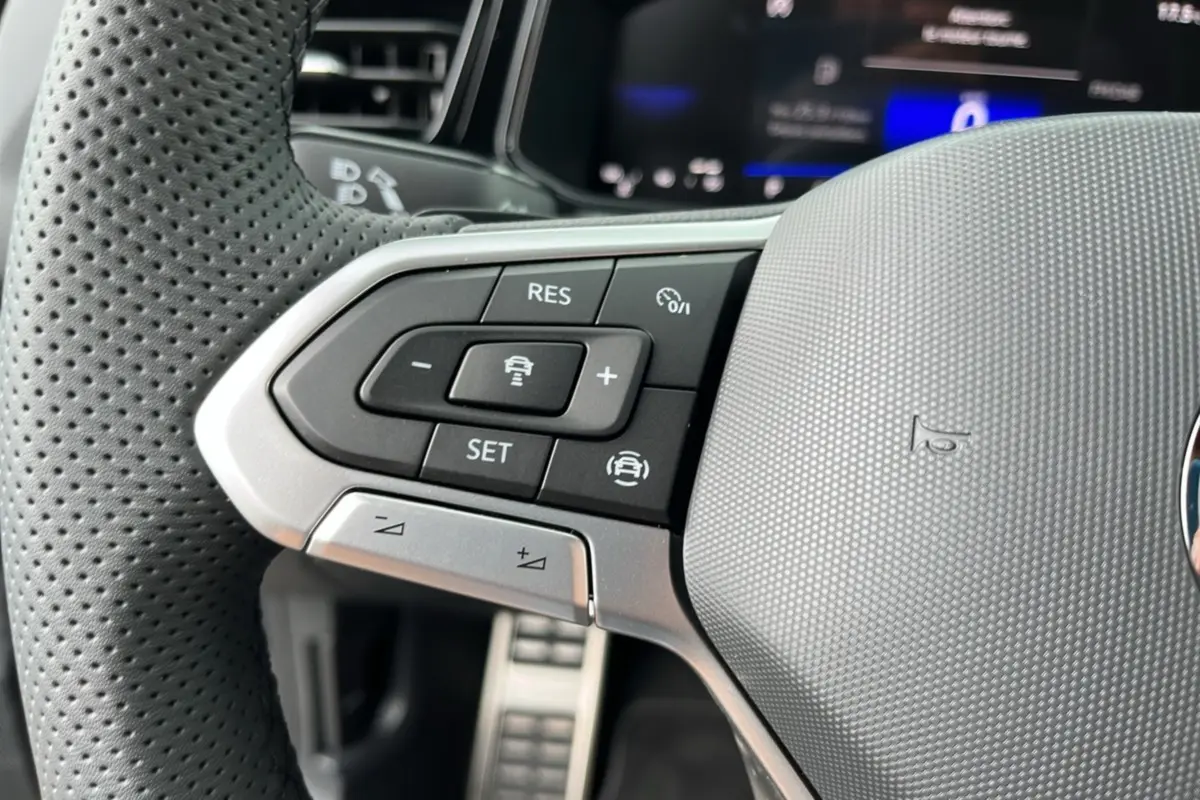 Gros plan sur les commandes à gauche du volant perforé gris du Volkswagen T-Roc TDI 150 DSG7 R-Line Black 2025.