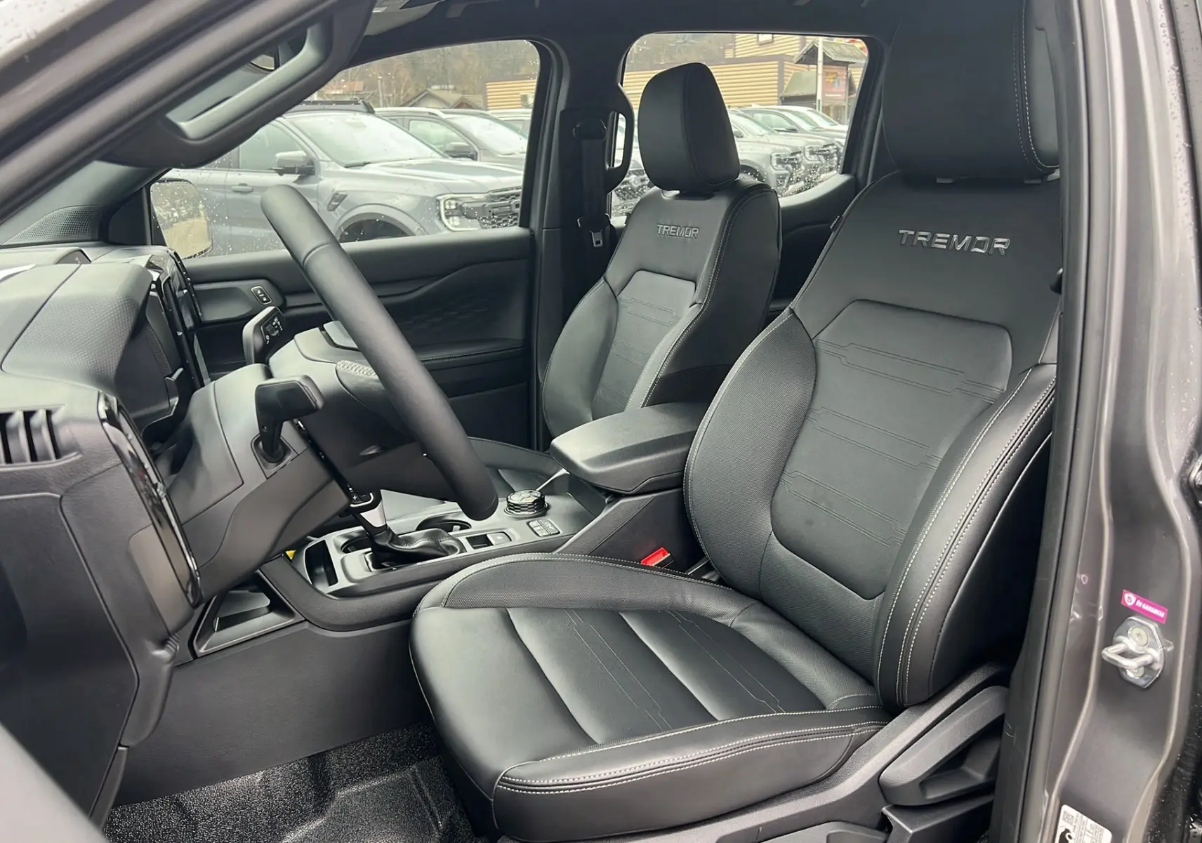 Intérieur du Ford Ranger 2025 gris carbone, vue côté gauche sur les sièges en cuir noirs avec logo Tremor brodé.