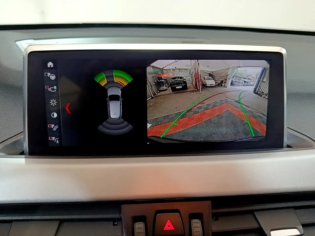 Écran multimédia affichant la caméra de recul et les capteurs de distance du BMW X1 noir, vue intérieure du tableau de bord.