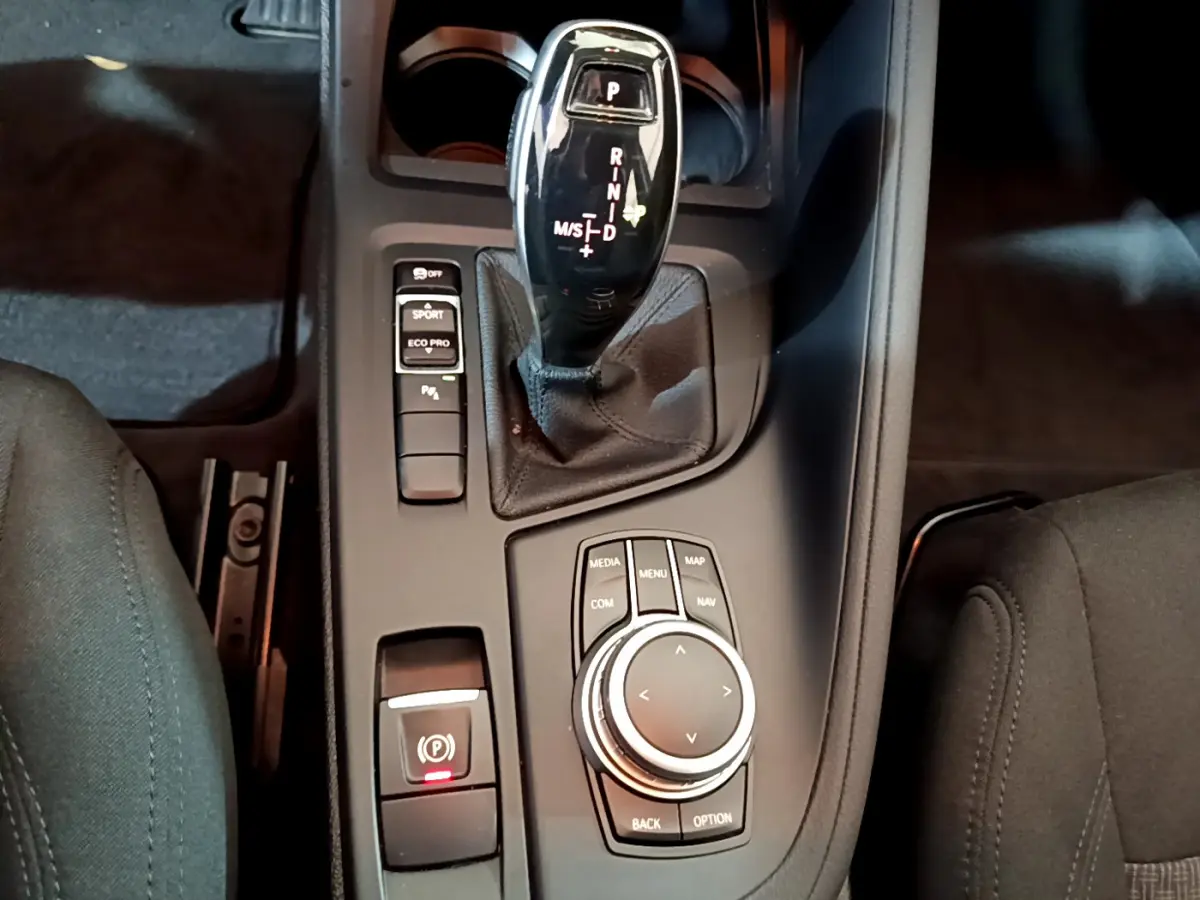 Vue rapprochée de la console centrale noire du BMW X1 2021, avec levier de vitesse automatique et molette de contrôle.