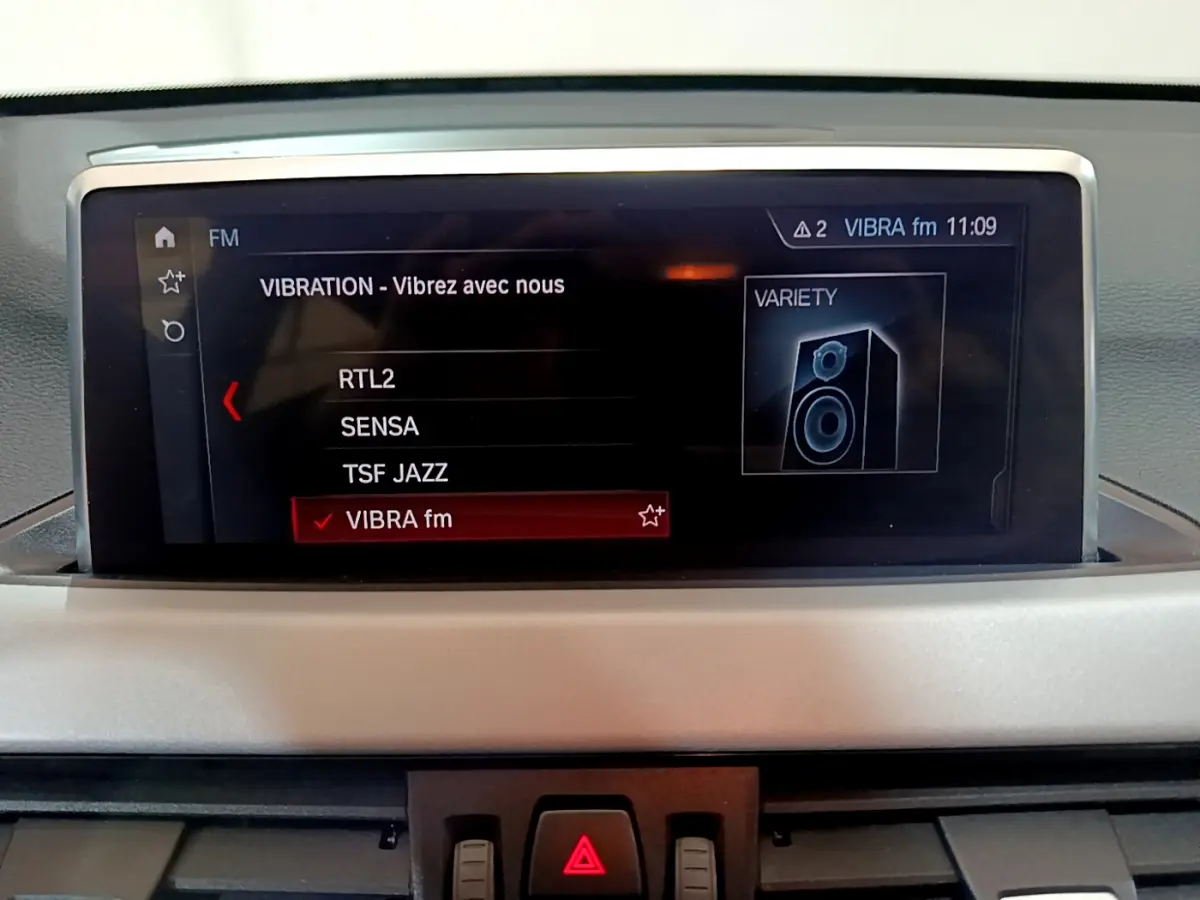 Écran multimédia du tableau de bord de la BMW X1 sDrive16d Lounge 2021 affichant les stations radio FM.