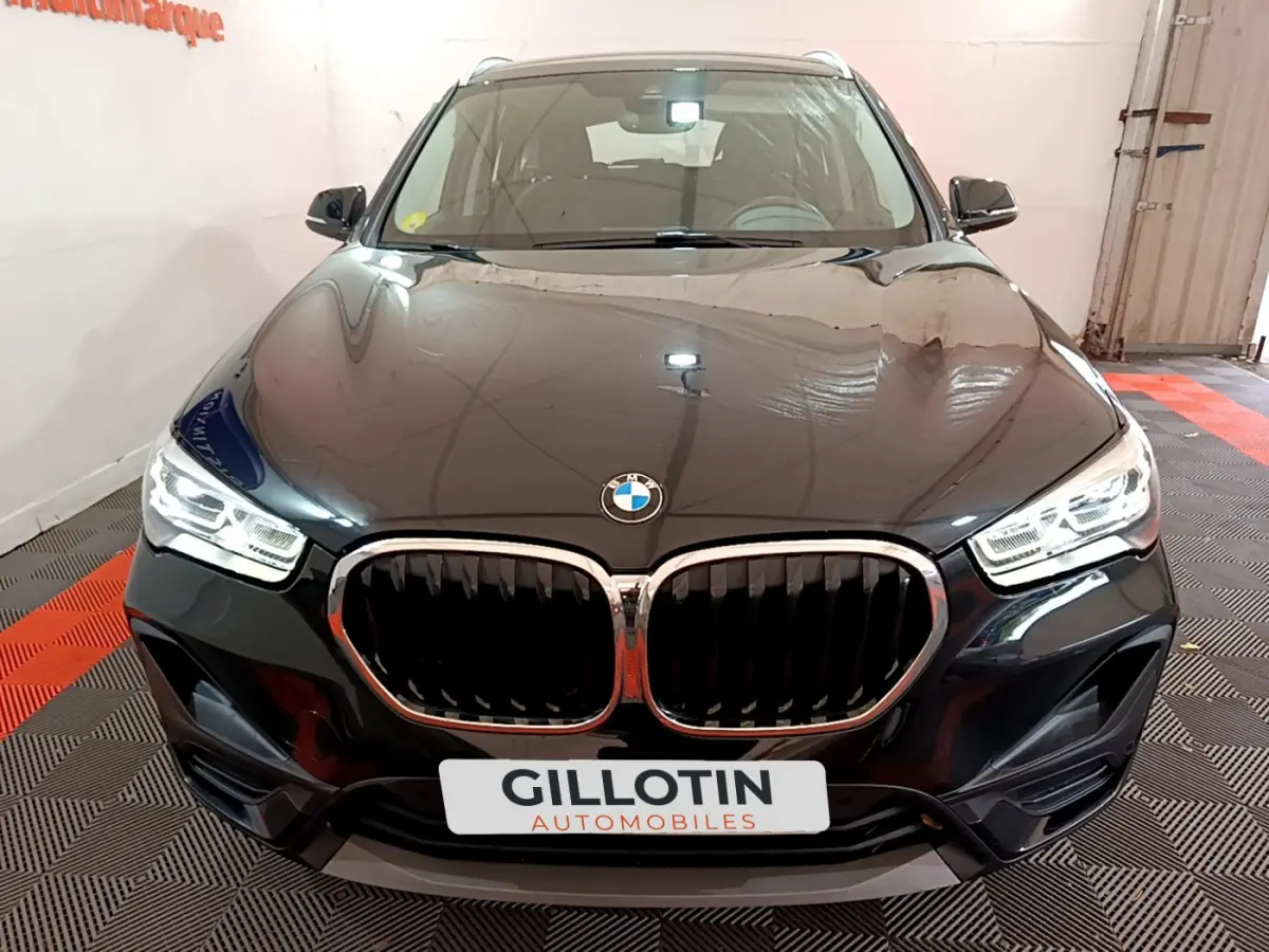 Vue avant d’un BMW X1 sDrive16d Lounge noir avec calandre double haricot et phares LED allumés.