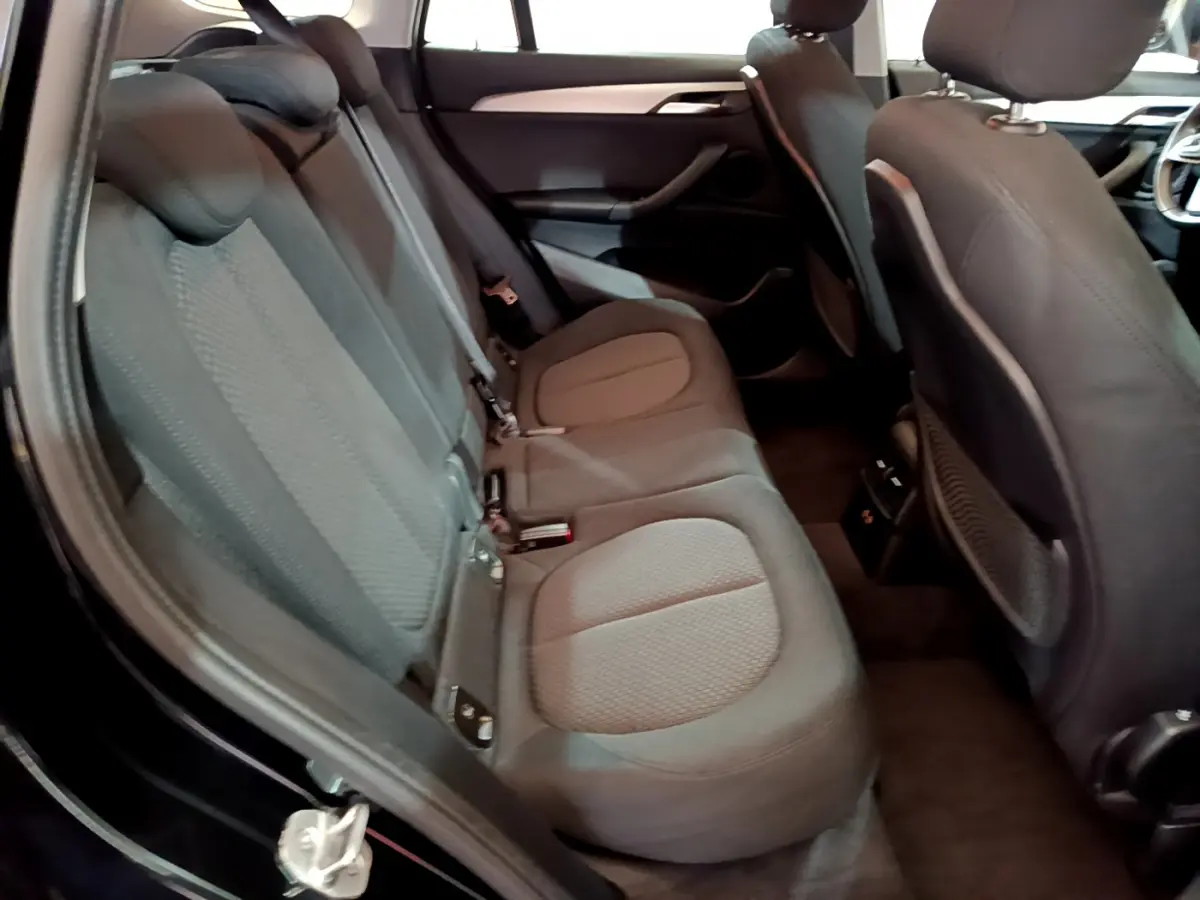 Vue intérieure côté gauche des sièges arrière du BMW X1 noir, montrant les assises en tissu et les dossiers avant.