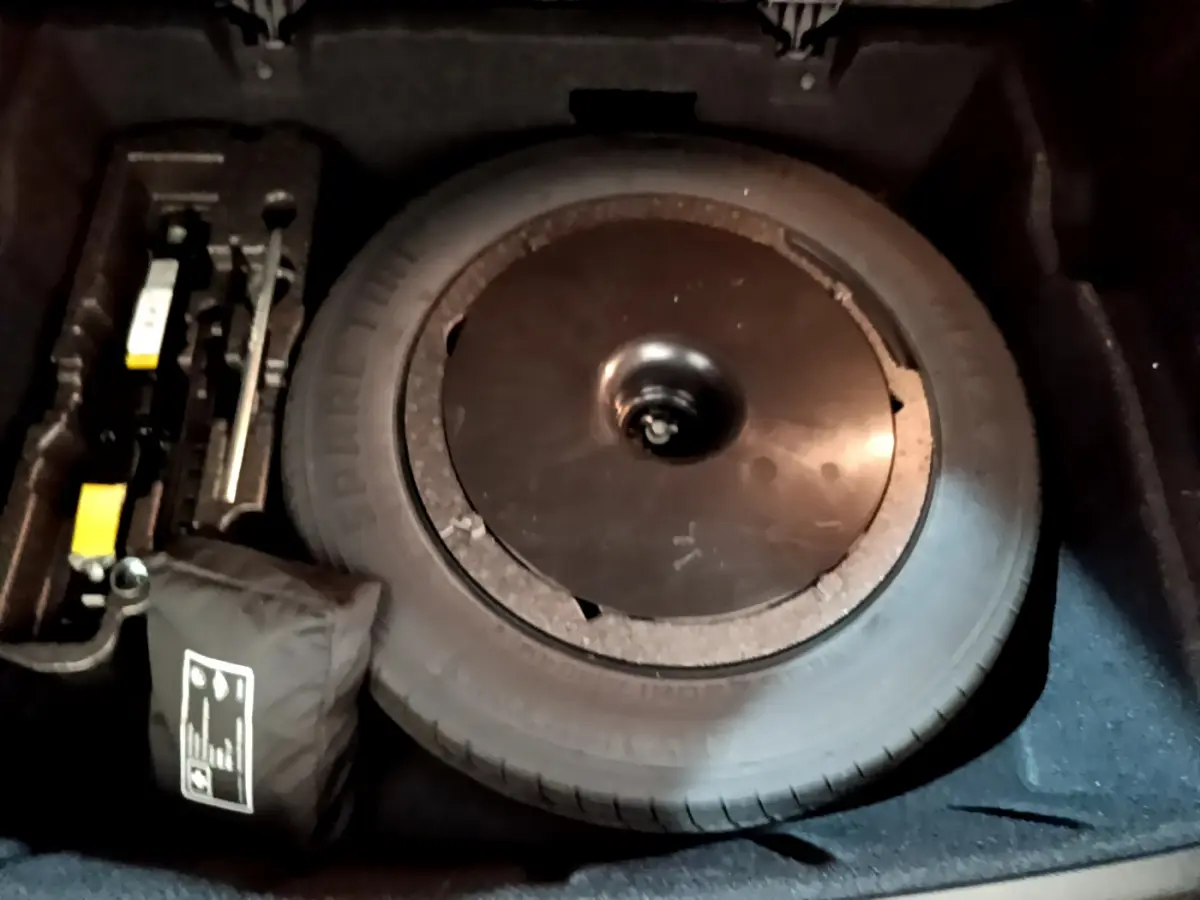 Vue rapprochée de la roue de secours et des outils dans le coffre du BMW X1 sDrive16d noir de 2021.