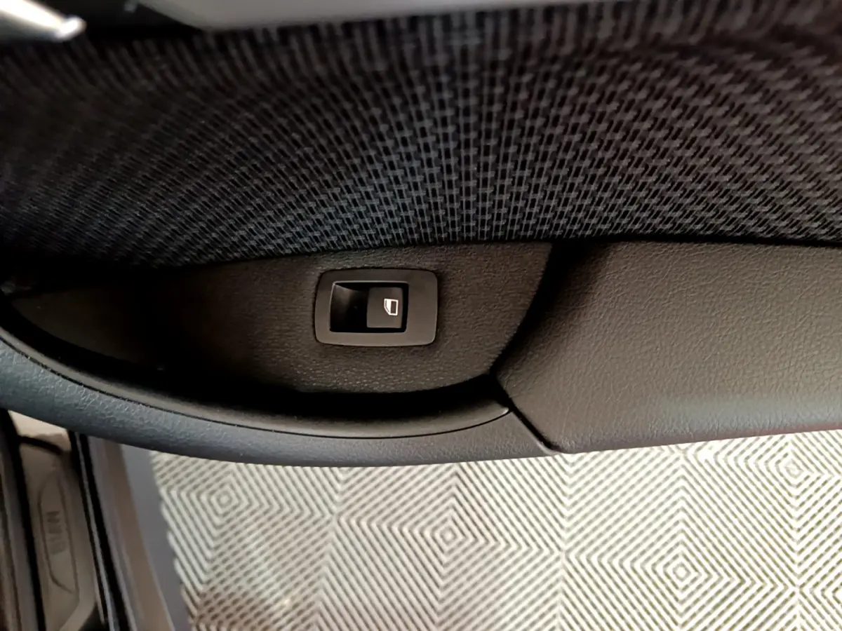 Bouton de fermeture électrique du coffre sur panneau intérieur noir d’une BMW X1 sDrive16d Lounge 2021.