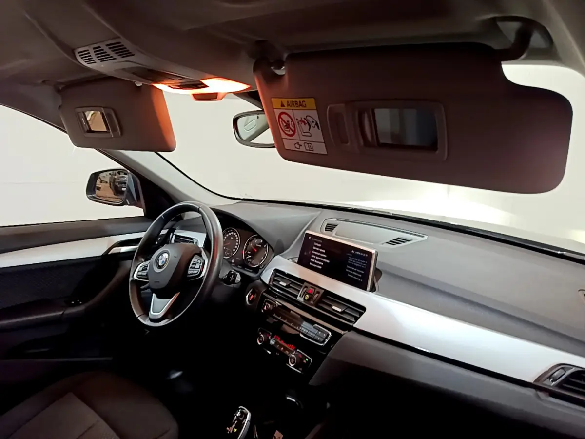 Vue intérieure côté conducteur du BMW X1 2021, tableau de bord avec écran central et volant cuir multifonctions.