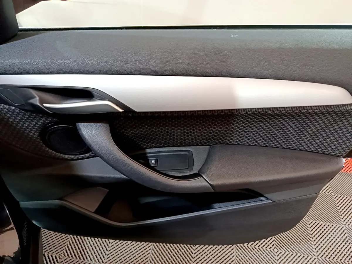 Gros plan sur la porte intérieure côté gauche de la BMW X1 sDrive16d Lounge 2021, avec insert gris et tissu texturé noir.