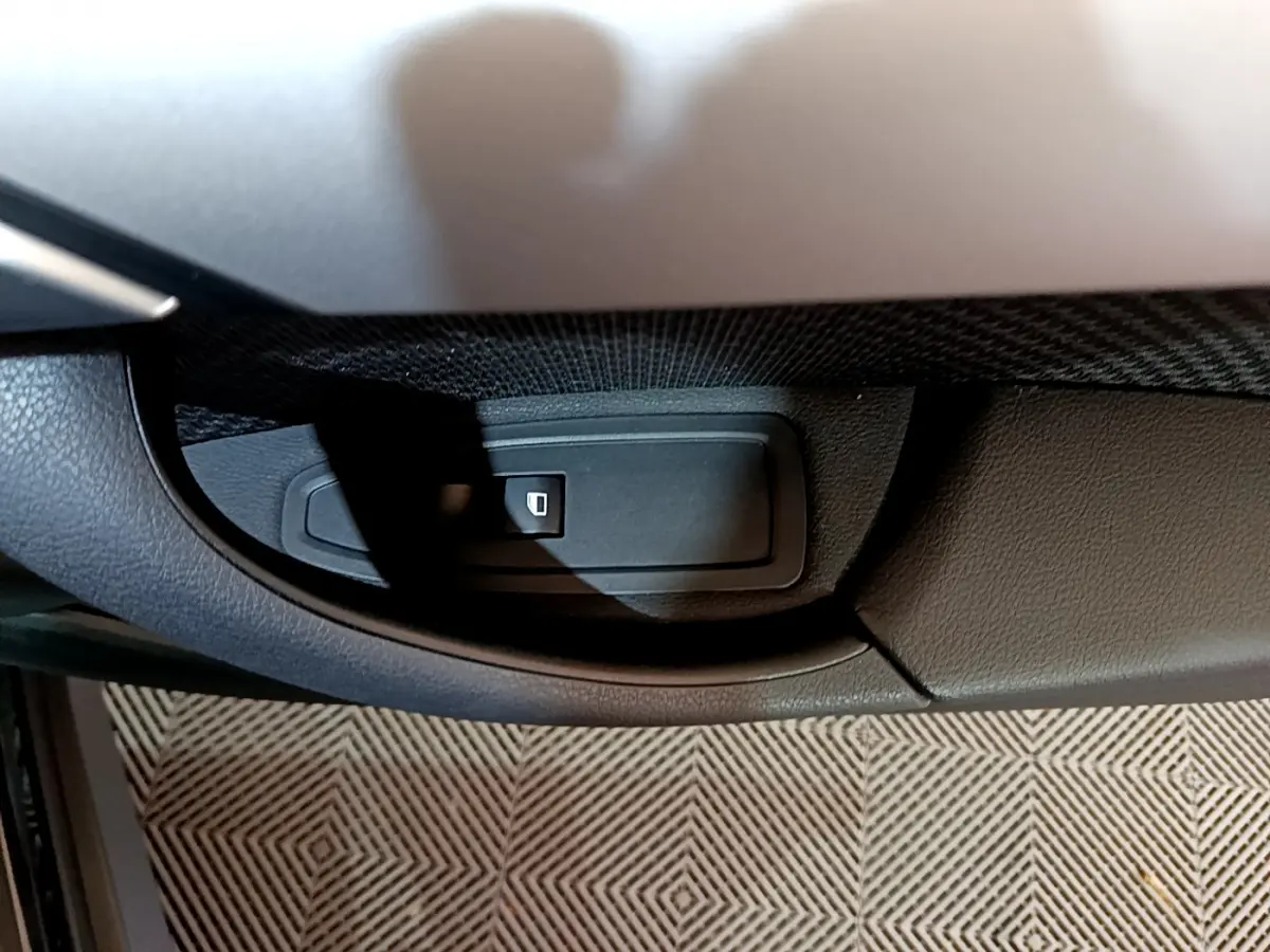 Gros plan sur le bouton de verrouillage centralisé dans la portière côté conducteur d’un BMW X1 noir 2021.