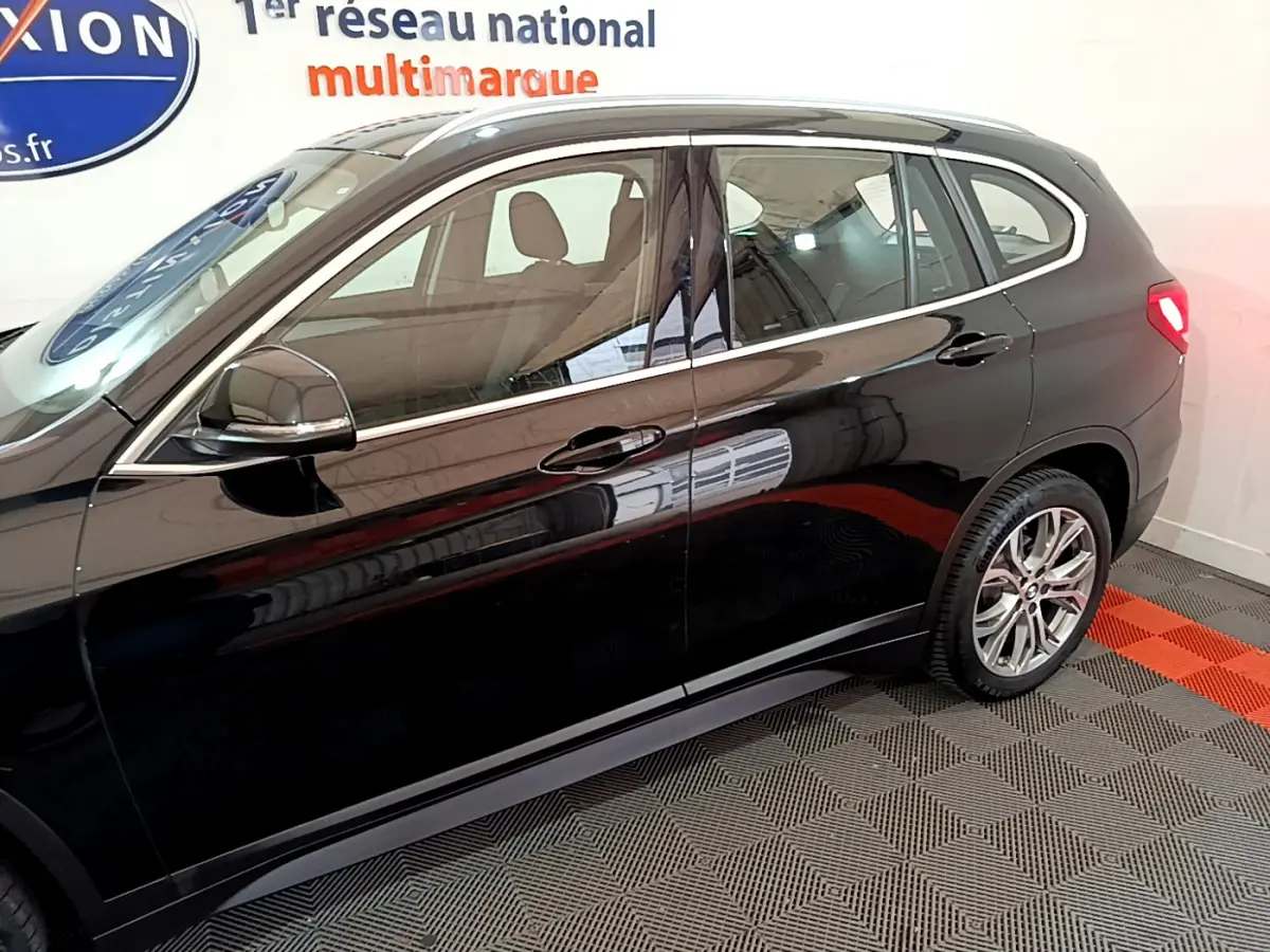 Vue latérale droite d'un BMW X1 noir 2021 avec jantes alliage et rétroviseurs noirs brillants.