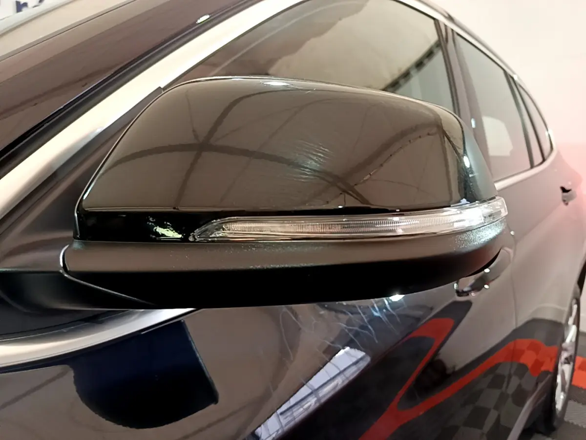 Gros plan sur le rétroviseur côté gauche noir brillant d’un BMW X1 sDrive16d Lounge DKG7 2021.