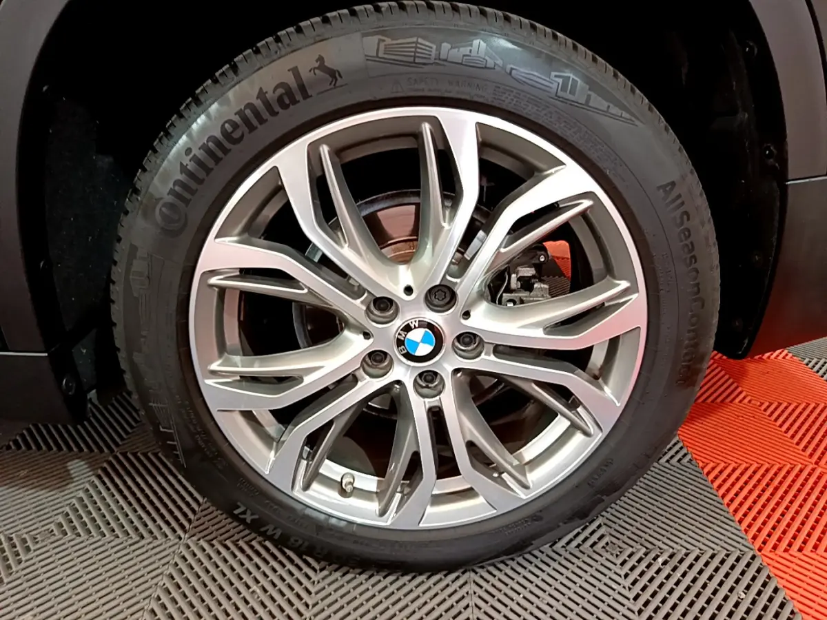Vue rapprochée sur la roue arrière droite d’un BMW X1 noir, mettant en valeur le pneu Continental AllSeasonContact.