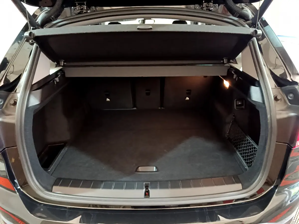 Coffre ouvert vu de l'arrière d'un BMW X1 noir 2021, espace de chargement spacieux avec cache-bagages relevé.