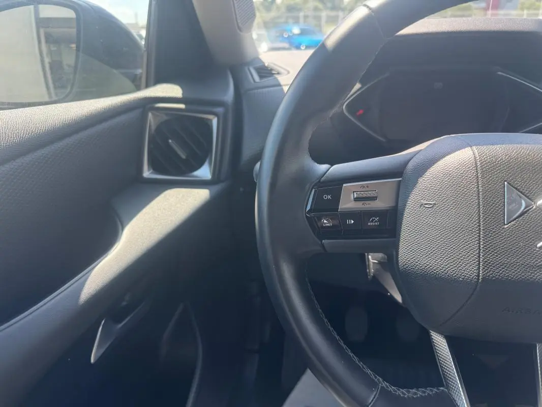 Vue intérieure côté conducteur du DS3 2024 gris, avec volant multifonction et commande d'assistance au pilotage.