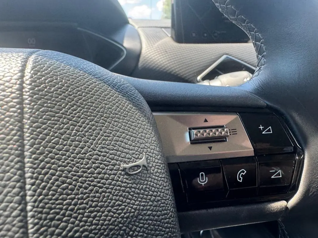Gros plan sur le volant noir texturé du DS3 100 BVM6 Bastille 2024 avec commandes audio et téléphone intégrées.