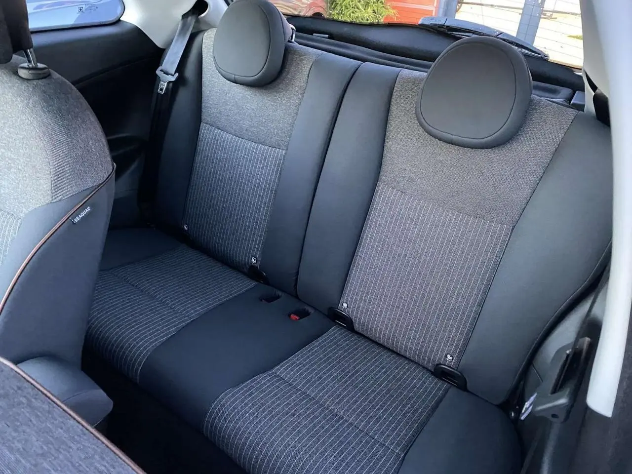 Vue intérieure arrière montrant les sièges arrière gris et noirs du Fiat 500 électrique blanc 2022.