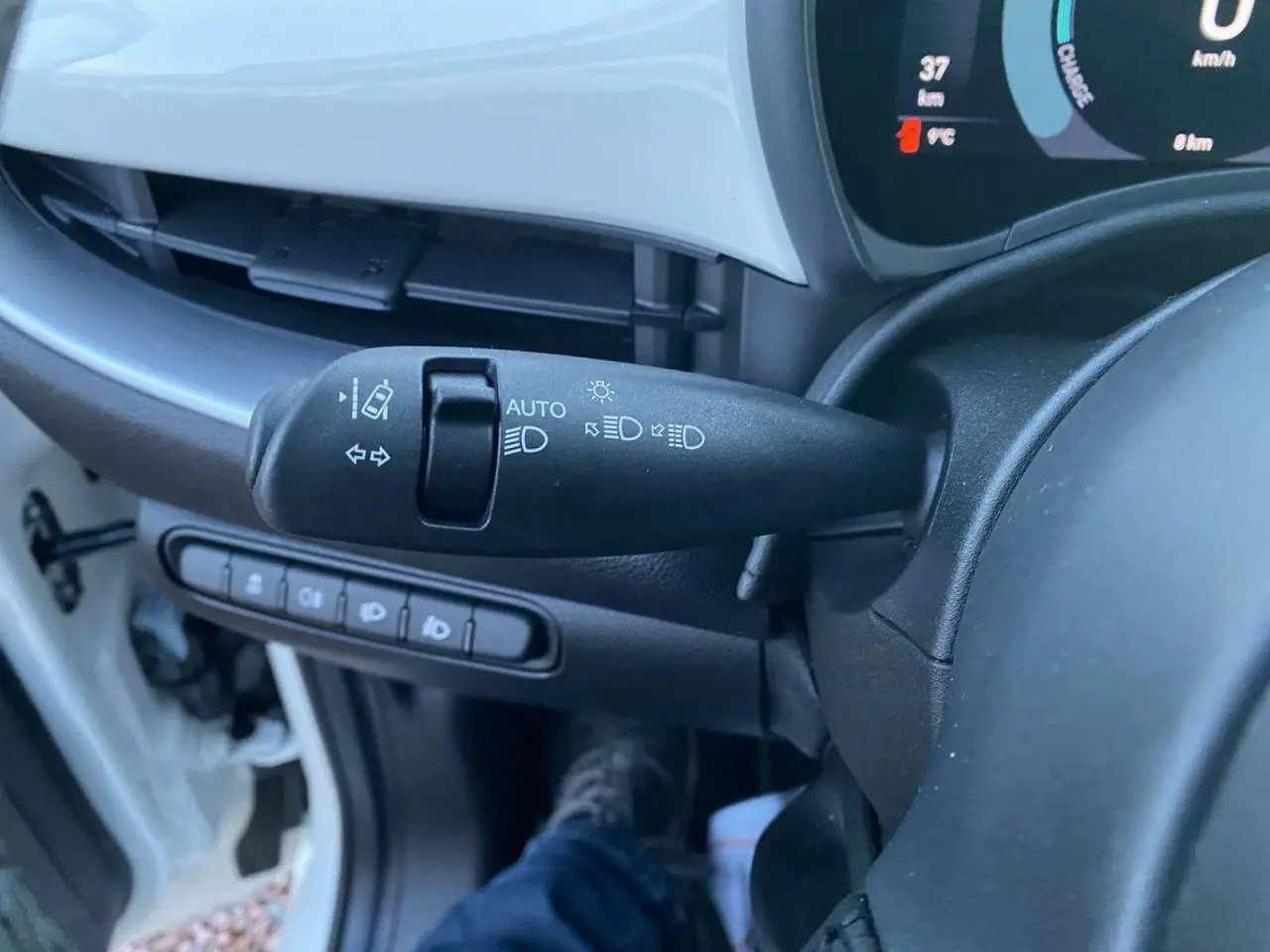 Le levier de commande des phares et clignotants dans l'habitacle d'une Fiat 500 électrique blanche, vue côté conducteur.