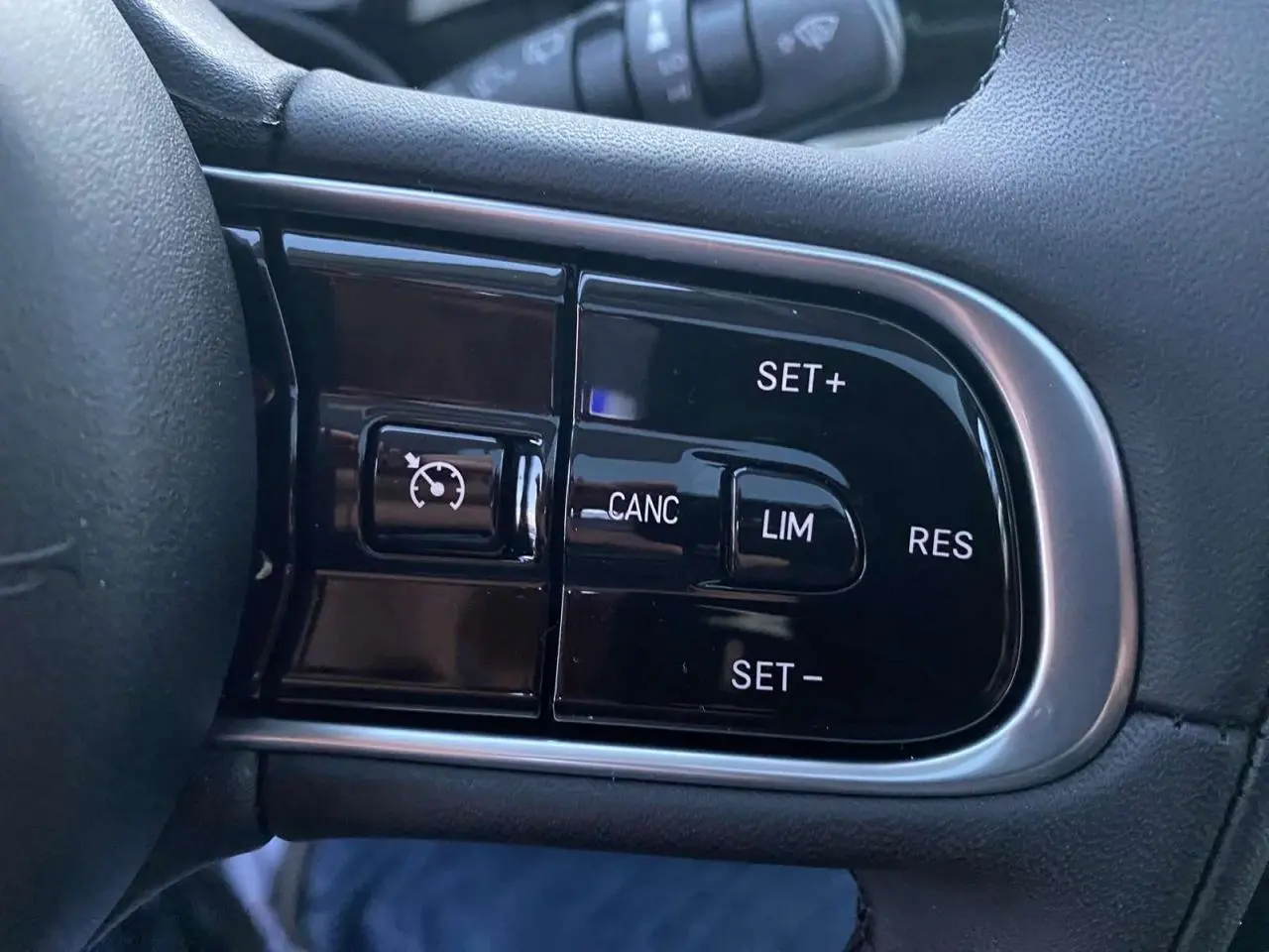 Gros plan sur les commandes du régulateur de vitesse à droite du volant de la Fiat 500 électrique blanche.