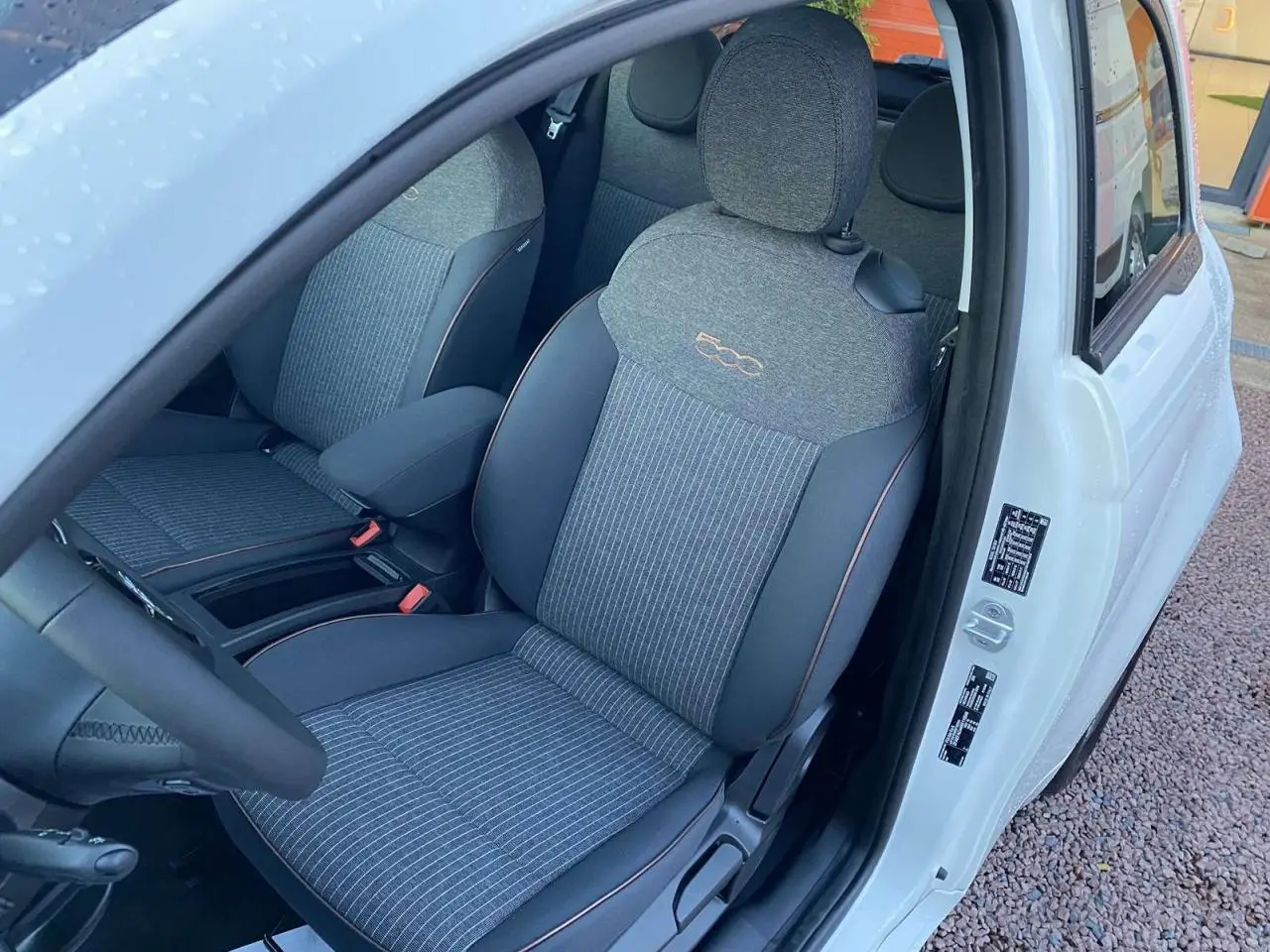 Vue intérieure côté conducteur du siège avant gris avec logo 500 brodé sur une FIAT 500 électrique blanche 2022.