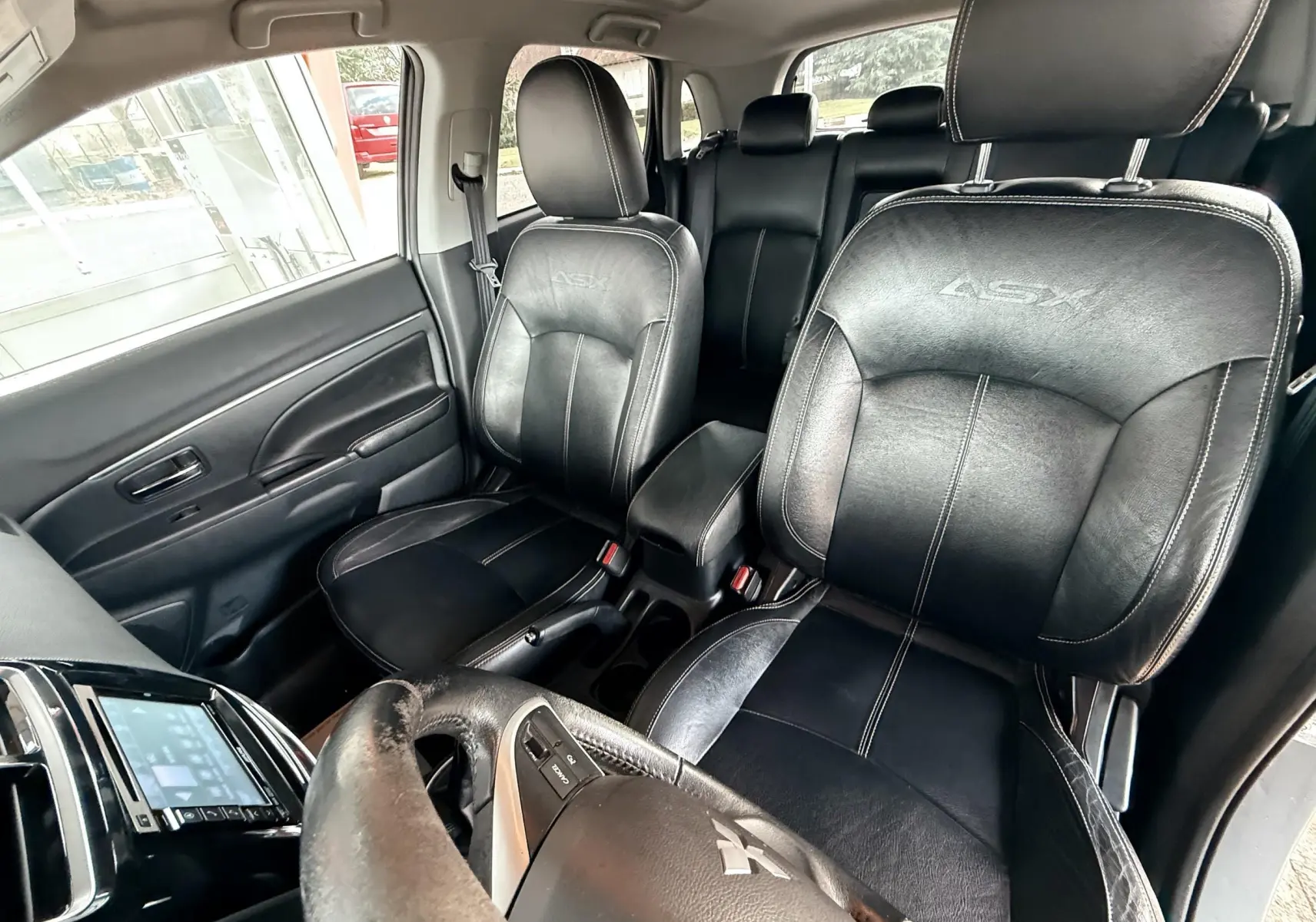 Vue intérieure avant du Mitsubishi ASX 2015 montrant les sièges en cuir noir avec logo ASX brodé.