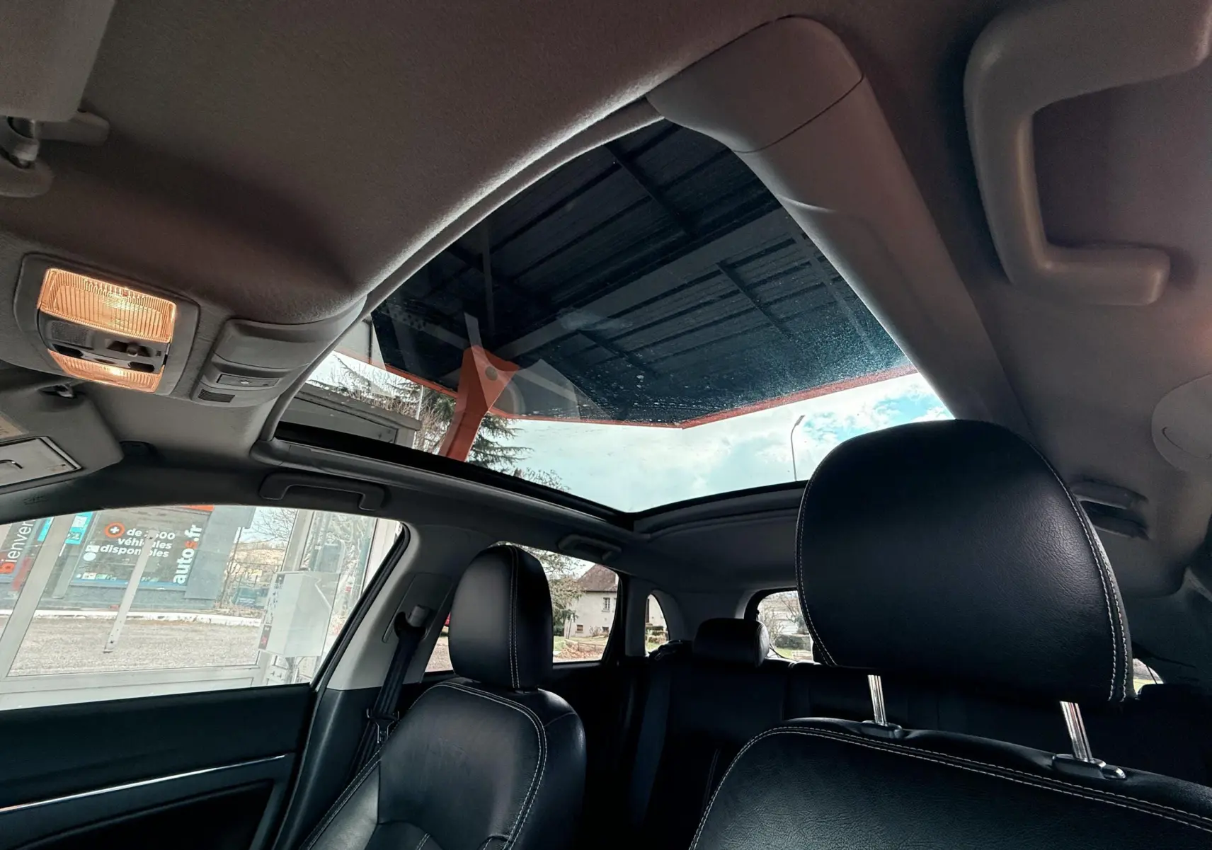 Vue intérieure du Mitsubishi ASX gris 2015 montrant les sièges en cuir noir et le toit ouvrant panoramique.