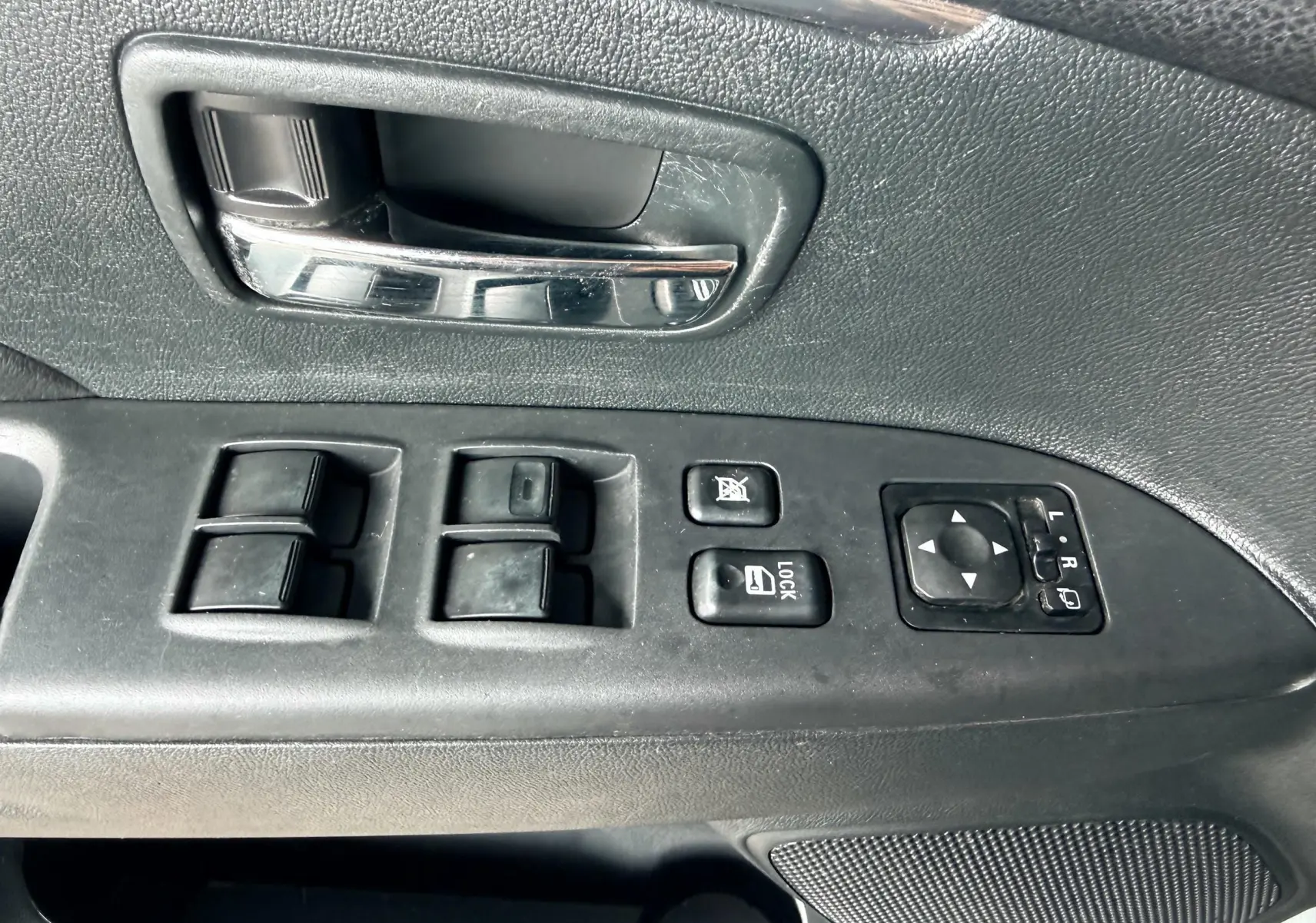 Gros plan sur la commande de lève-vitres et rétroviseurs côté conducteur du Mitsubishi ASX gris de 2015.