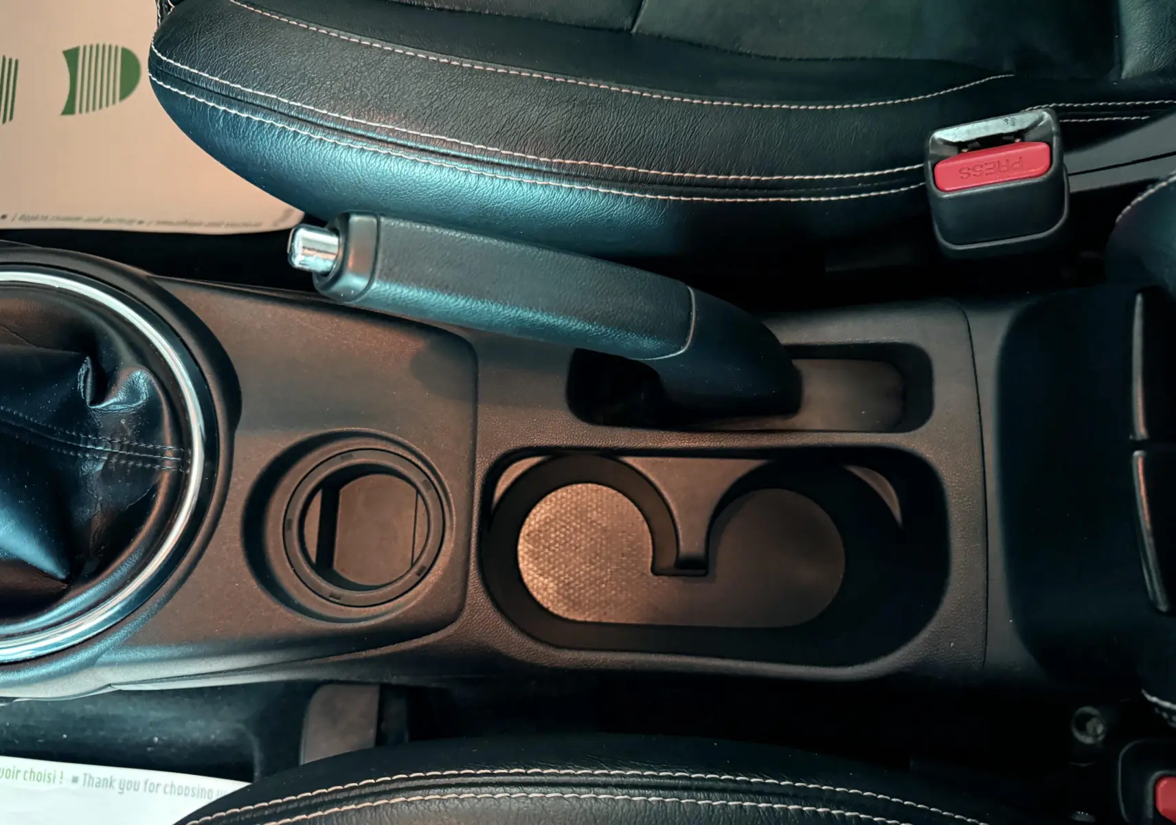 Vue plongeante sur la console centrale noire du Mitsubishi ASX 2015, avec frein à main et porte-gobelets.