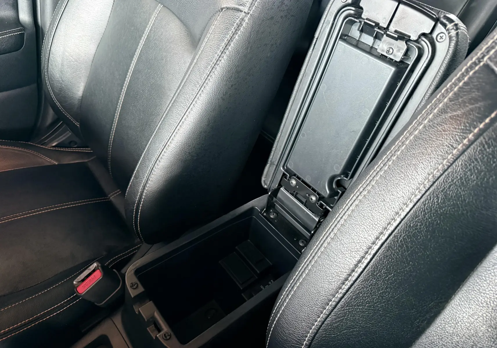 Vue rapprochée de l’intérieur du Mitsubishi ASX 2015 montrant l’accoudoir central en cuir noir ouvert entre les sièges avant.