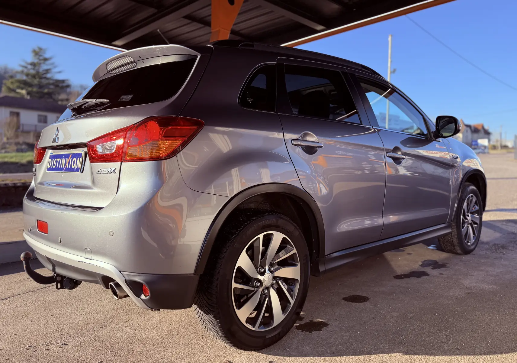 Vue 3/4 arrière droite du Mitsubishi ASX gris avec attelage et jantes alliage sous un abri.