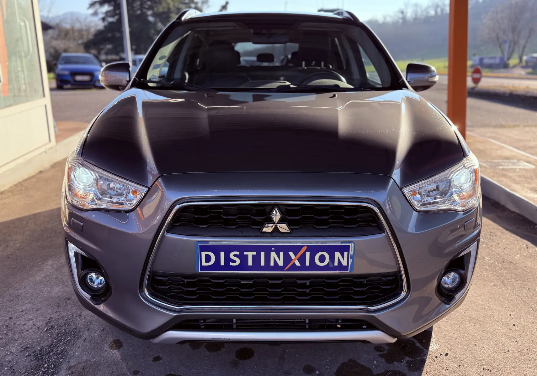 Vue avant d’un Mitsubishi ASX gris 2015 avec calandre noire et plaque Distinxion visible au centre.