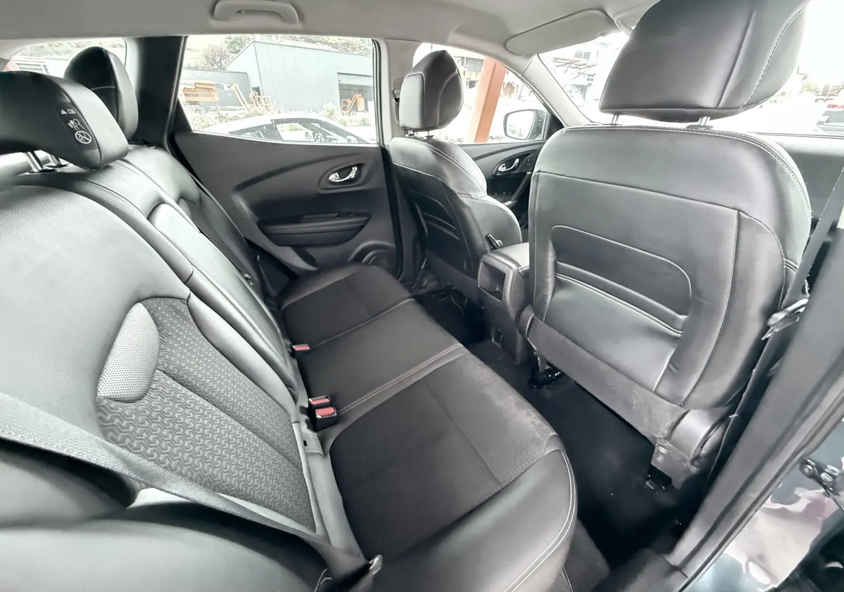 Vue intérieure arrière du Renault Kadjar 2016, sièges noirs en cuir et tissu, portes ouvertes côté droit.