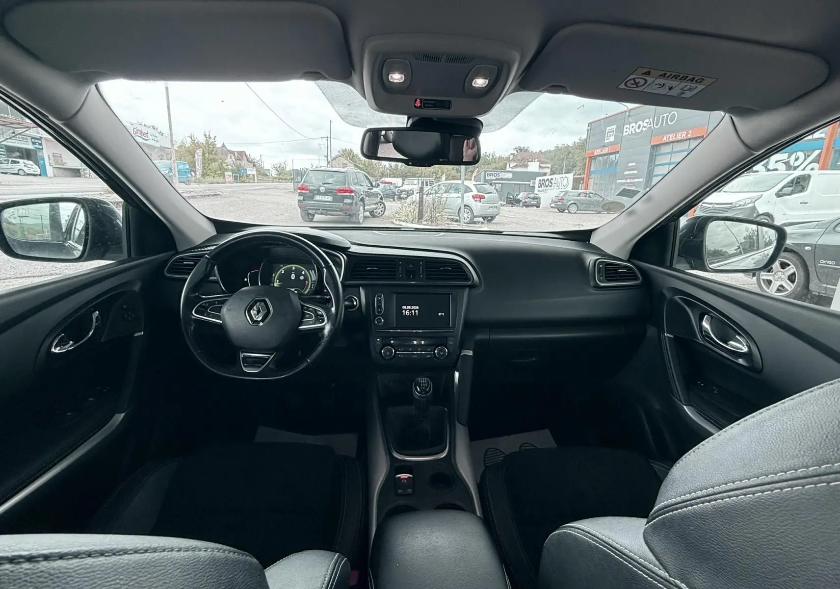 Intérieur noir du Renault Kadjar 2016, vue frontale du tableau de bord avec volant et boîte manuelle visible.
