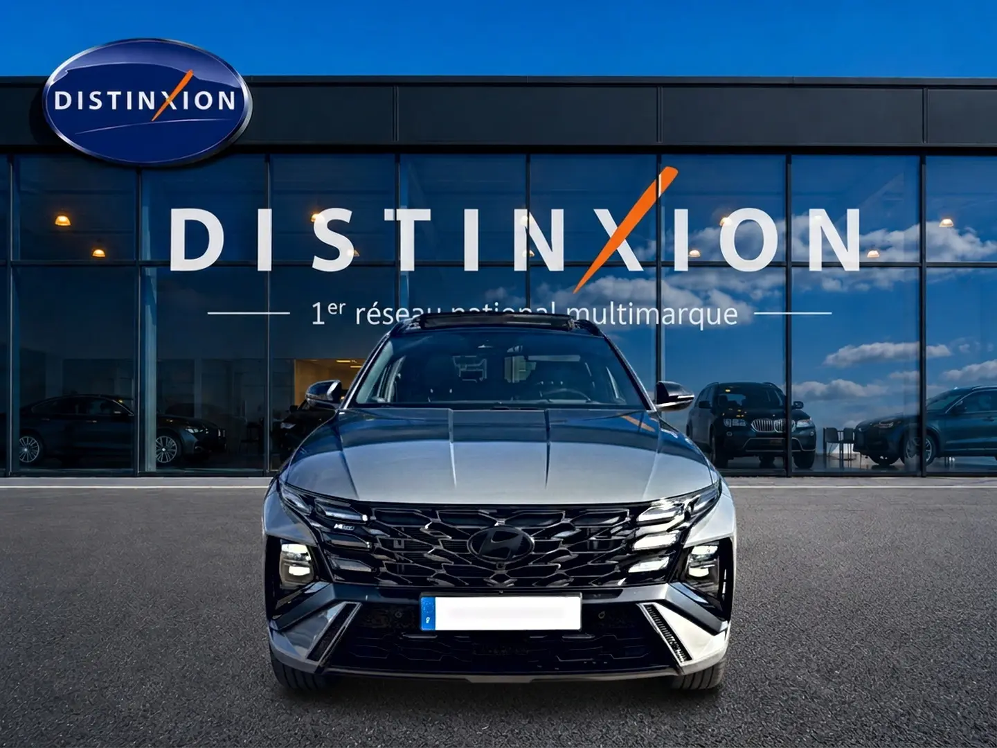 Vue avant du Hyundai Tucson gris shadow avec calandre noire et feux LED, devant une vitrine Distinxion.