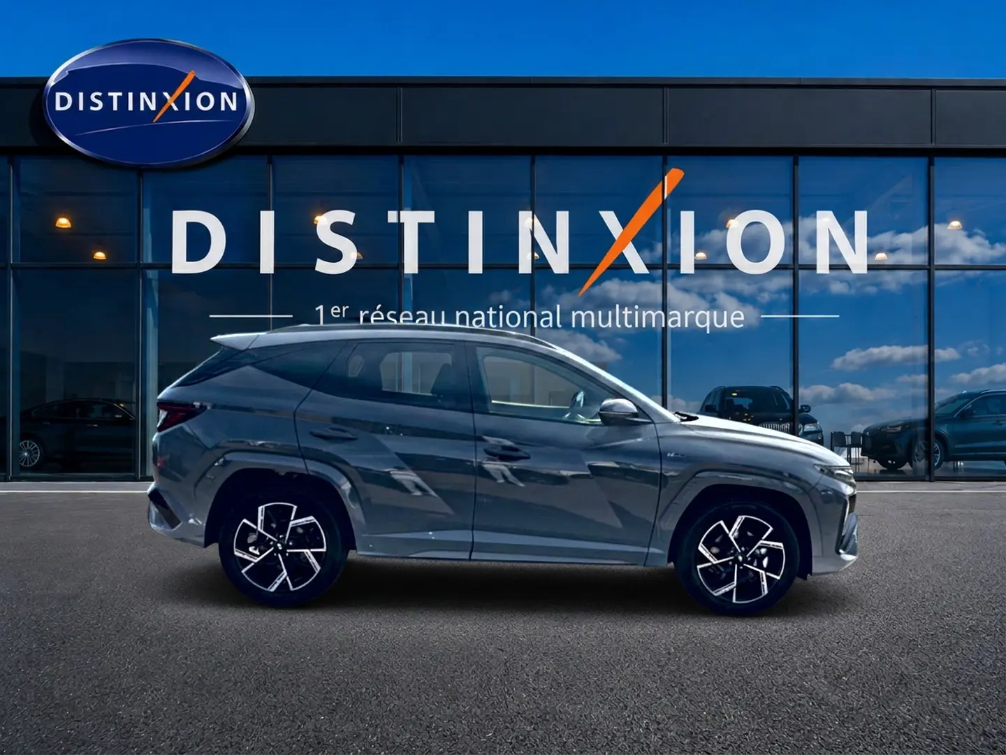 Vue de profil côté gauche du Hyundai Tucson gris shadow 2026 devant une vitrine Distinxion.
